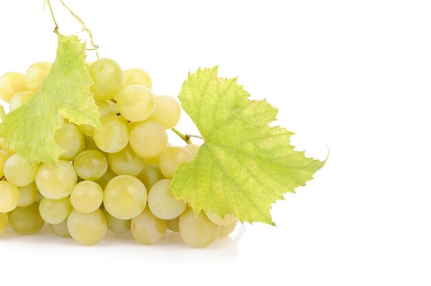 Uvas verdes frescas con hojas aisladas en blanco