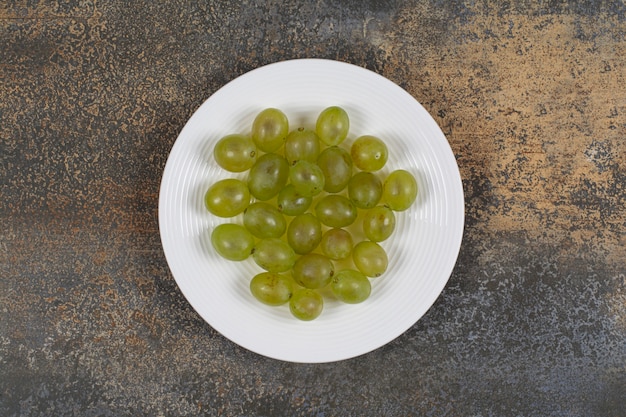 Uvas verdes frescas en un plato blanco.