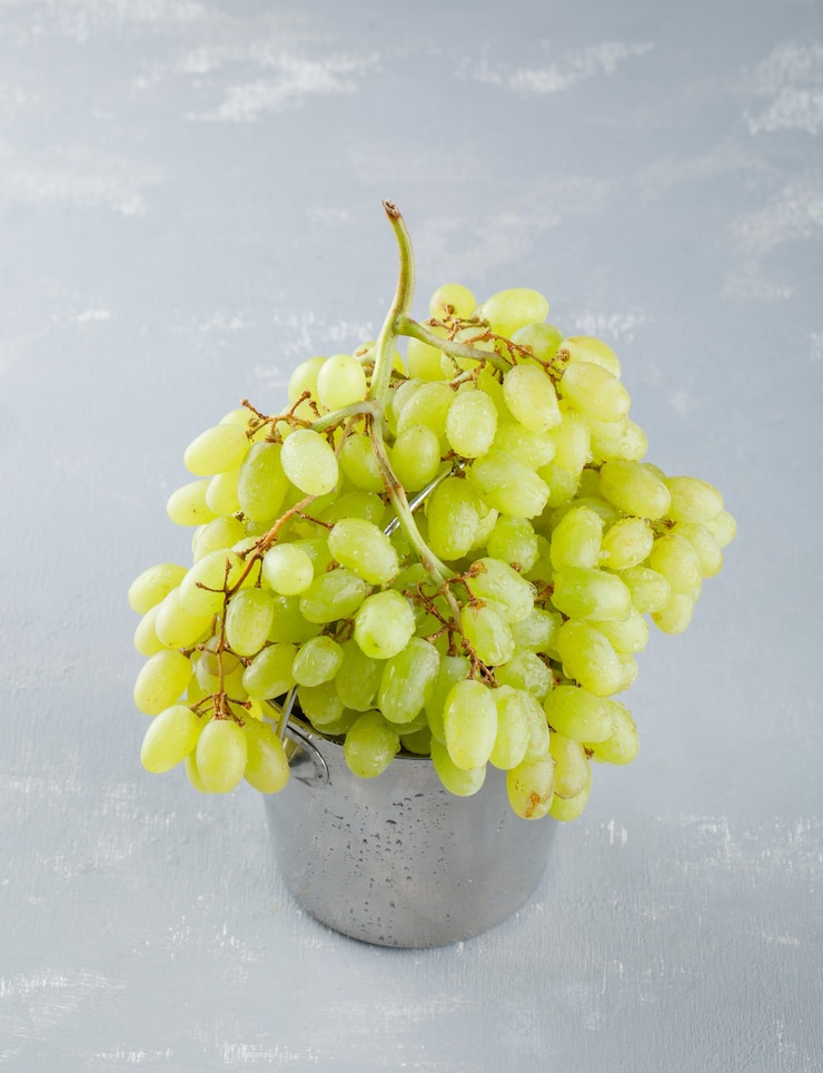 Foto gratuito uvas verdes en un mini balde sobre un yeso.