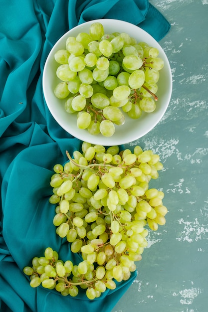 Foto gratuita uvas verdes en una placa sobre yeso y textil