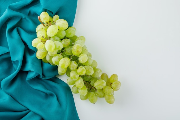 Uvas verdes sobre blanco y textil,