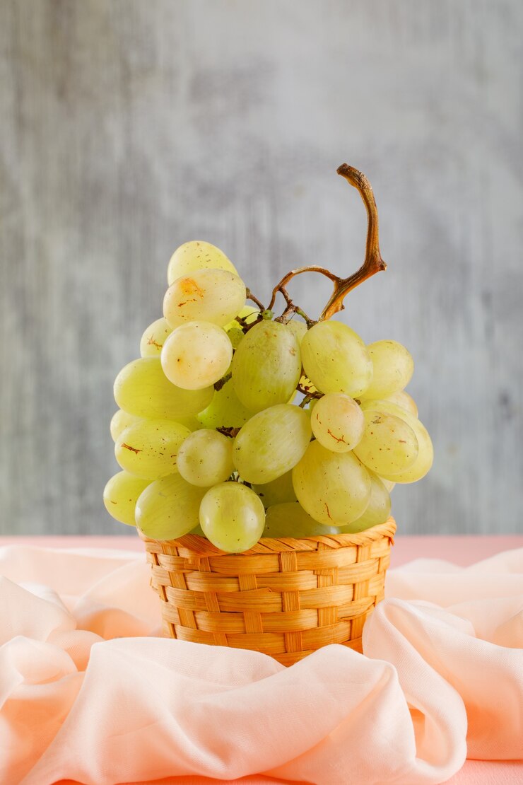 Foto gratuito uvas verdes con textil en una canasta de mimbre en rosa y borrosa,