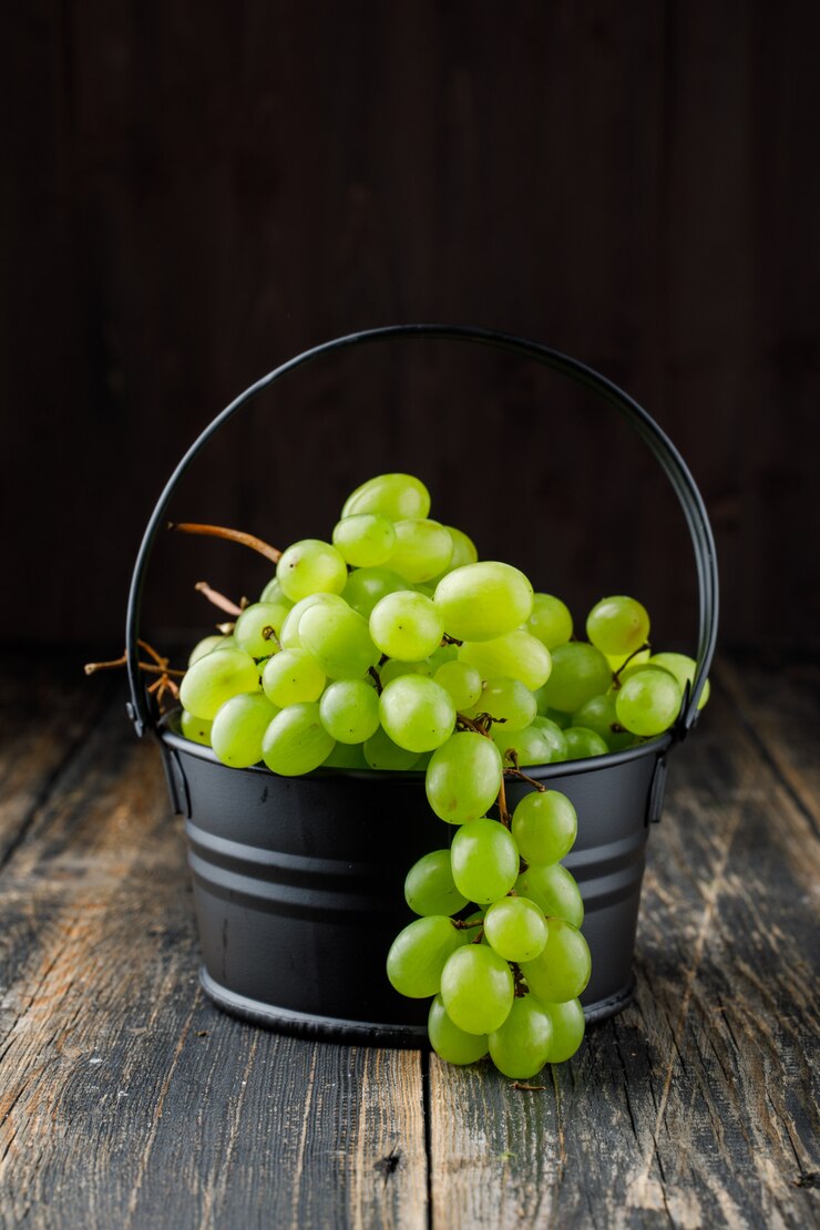 Foto gratuito uvas en una vista lateral mini cubo sobre una superficie de madera