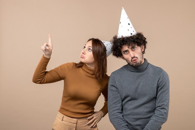 Vacaciones festivas y concepto de fiesta - feliz pareja divertida amorosa que se siente sorprendida en gris