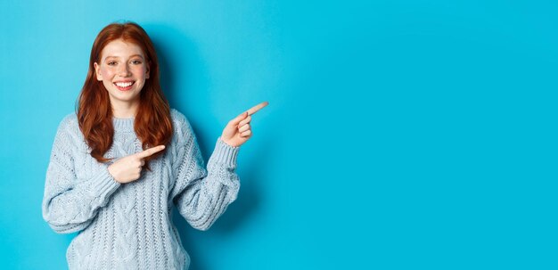 Vacaciones de invierno y el concepto de la gente bonita adolescente con el pelo rojo apuntando con el dedo directamente al logo