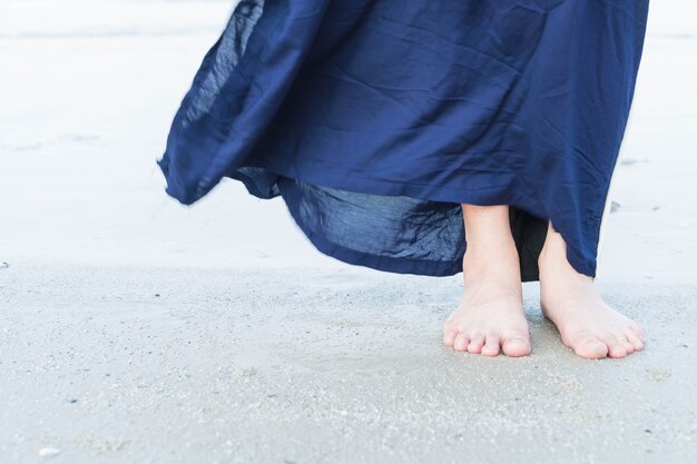 Vacaciones. Mujer pies de cerca de niña de relax en la playa