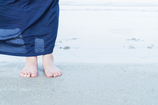 Vacaciones. Mujer pies de cerca de niña de relax en la playa