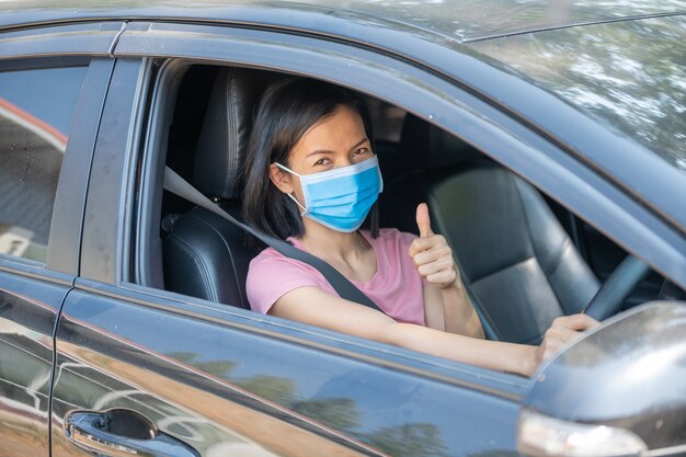 Vacaciones de vacaciones, Coronavirus Covid-19 y mascarilla, Mujer con mascarilla conduciendo su automóvil durante la pandemia de coronavirus, nueva normalidad para mantenerse a salvo, viaje de verano en automóvil.