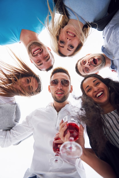 Foto gratuita vacaciones de verano, gente feliz: un grupo de adolescentes mirando hacia abajo con una sonrisa feliz en su rostro.