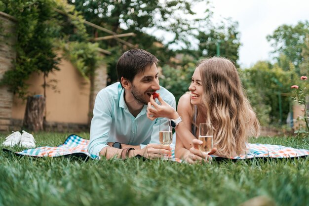 Vacaciones de verano, gente, romance, hombre y mujer dándose de comer fresas mientras beben y disfrutan del tiempo juntos en casa.