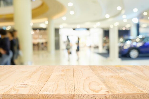 Vaciar la plataforma de madera del espacio de la mesa con la alameda de compras borrosa o el fondo del centro comercial para el montaje de la exhibición del producto. Escritorio de madera con copia espacio.