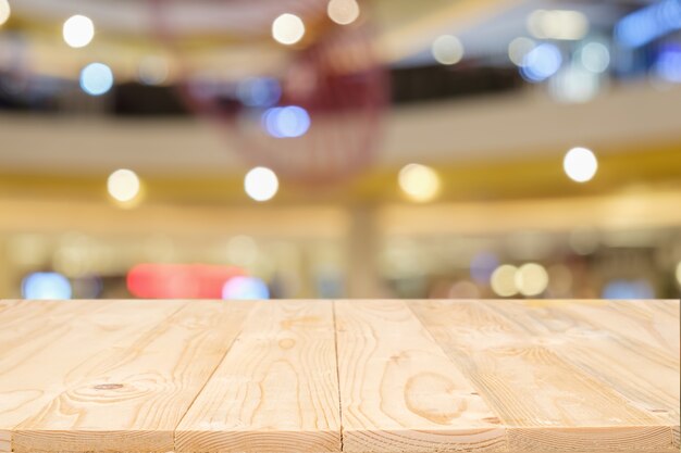Vaciar la plataforma de madera mesa de espacio y borrosa centro comercial o centro comercial de fondo para el montaje de la pantalla del producto. Escritorio de madera con copia espacio.