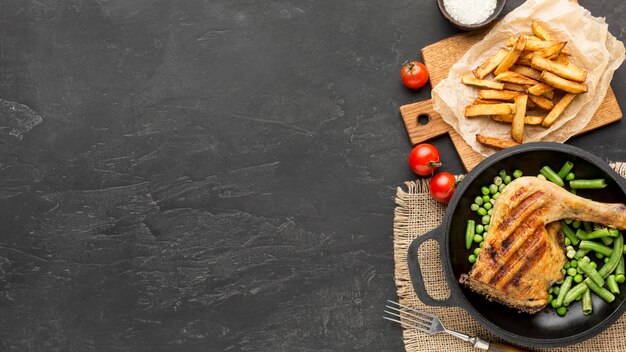 Vainas planas de pollo y guisantes al horno en una sartén con patatas y espacio de copia