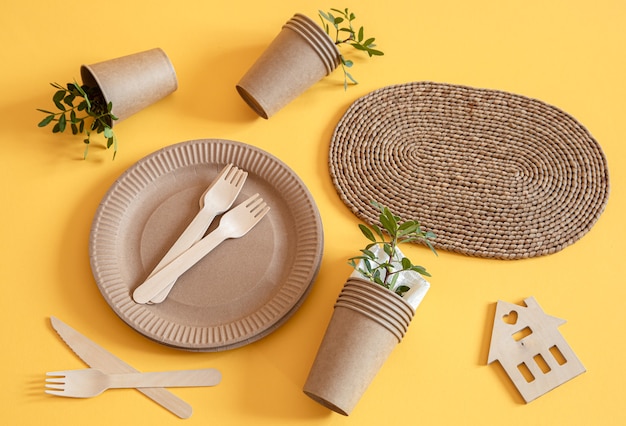 Vajilla de papel reciclable elegante y ecológica. Cajas de comida de papel, platos y cubiertos de maicena sobre un fondo naranja de tendencia.