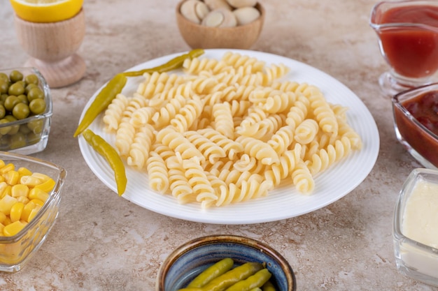 Vajilla con plato principal rodeado de aderezos y aperitivos sobre superficie de mármol