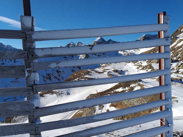 Valla de madera cubierta de nieve detrás de las montañas