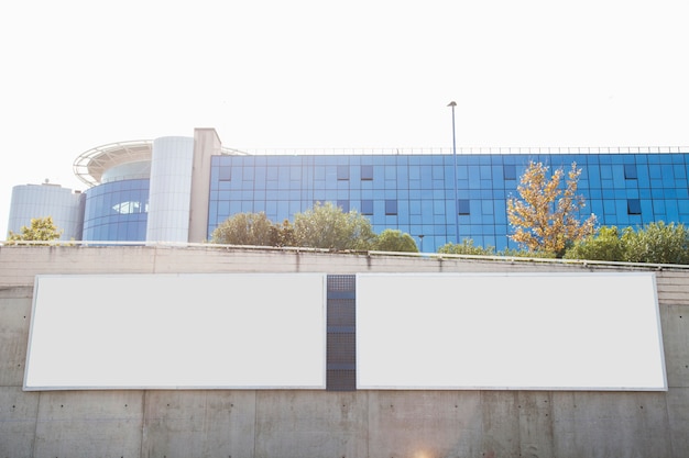 Vallas publicitarias blancas en blanco en el muro de concreto frente al edificio corporativo