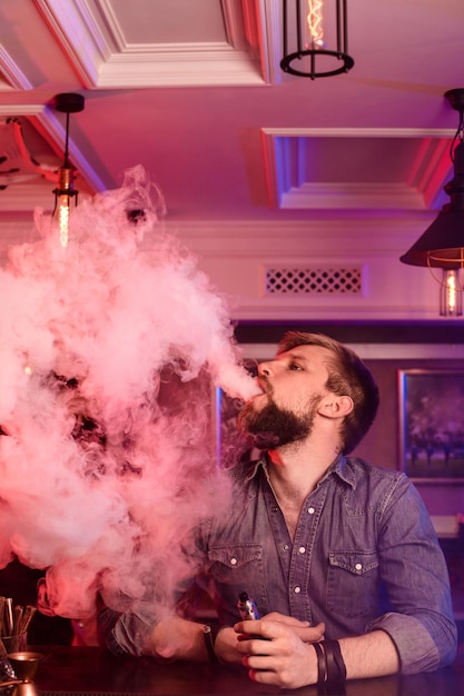 Vape. Hombre vaping en una nube de vapor. La foto está tomada en un bar de vape. tienda de vapeo