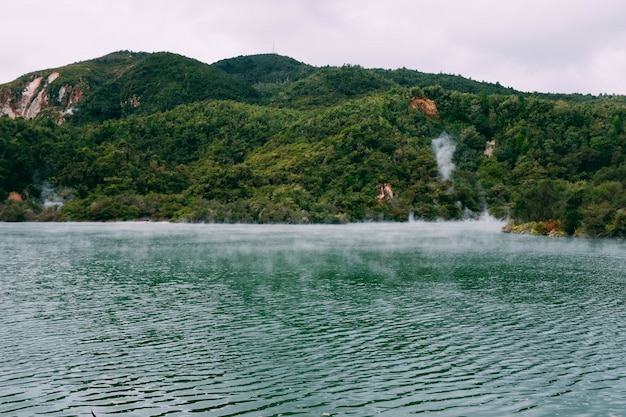 Foto gratuita vapor saliendo de un hermoso cuerpo de agua rodeado de montañas verdes