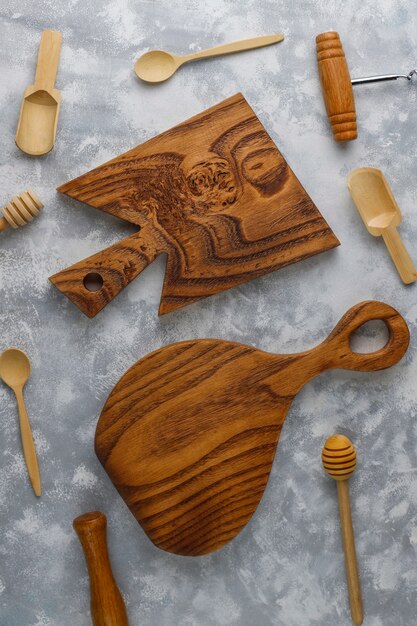 Varias cucharas de madera con tabla de cortar de madera hecha a mano sobre hormigón gris