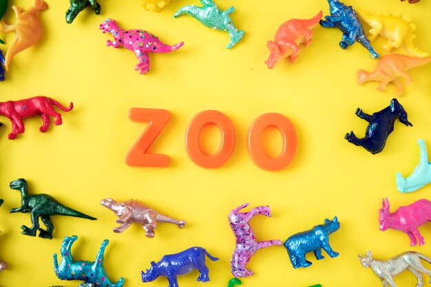 Varias figuras de juguete de animal de fondo con la palabra zoo