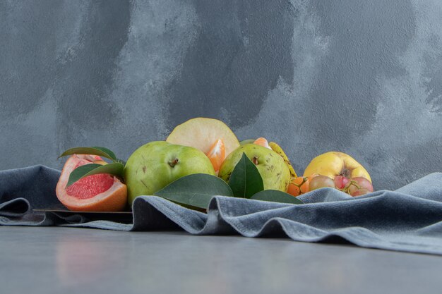 Varias frutas agrupadas en un trozo de tela sobre mármol