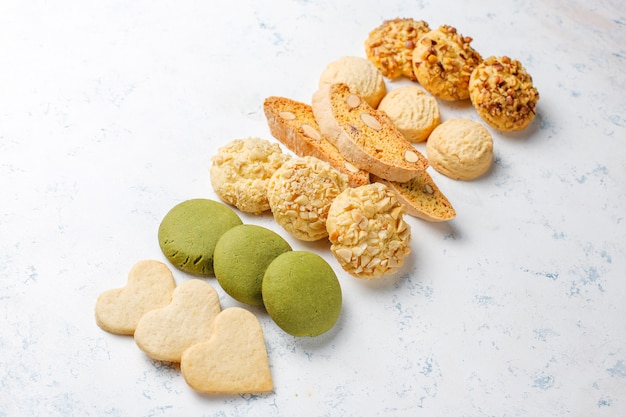 Varias galletas de nuez galletas de nuez, galletas de maní, galletas de almendras y galletas de matcha en la mesa de luz