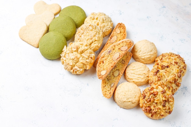 Varias galletas de nuez galletas de nuez, galletas de maní, galletas de almendras y galletas de matcha en la mesa de luz