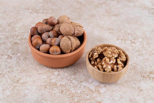 Varias nueces en cuenco de madera sobre superficie de mármol.