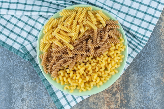 Varias pastas en un recipiente sobre la toalla, sobre la superficie de mármol.