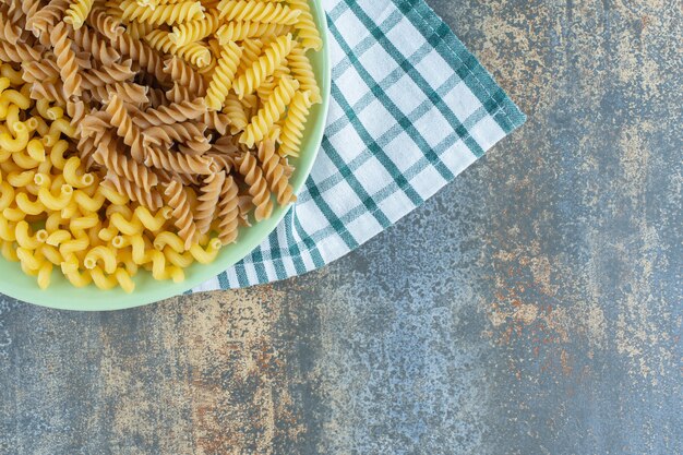 Varias pastas en un recipiente sobre la toalla, sobre la superficie de mármol.