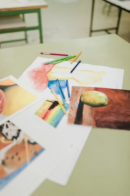 Varias pinturas en papel y lápices de colores en la mesa