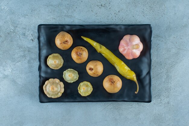 Varias verduras fermentadas en un plato sobre la superficie azul