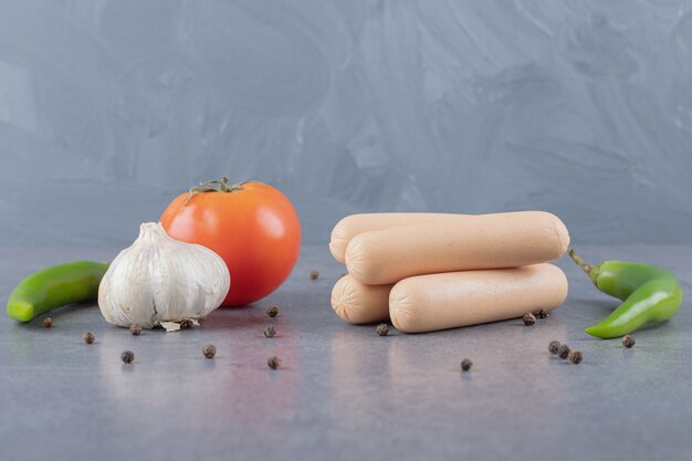 Varias verduras con salchichas en superficie de mármol