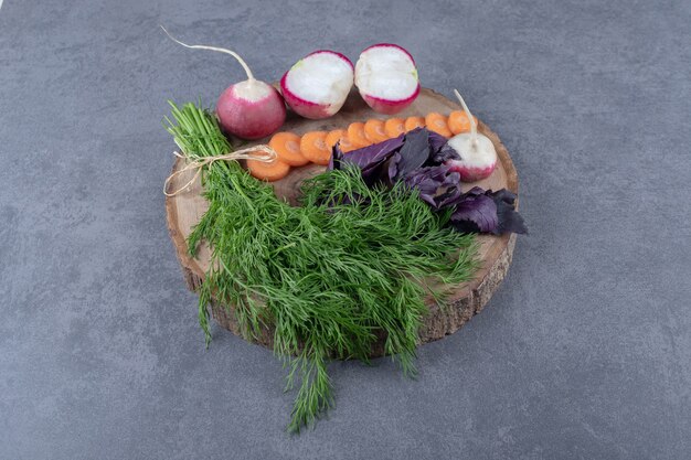 Varias verduras en un tablero, sobre la superficie de mármol.