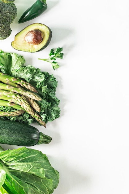 Varias verduras verdes frescas sobre un fondo blanco brócoli apio aguacate calabacín col rizada perejil pimiento picante hojas de lechuga Fondo de concepto de comida vegetariana saludable