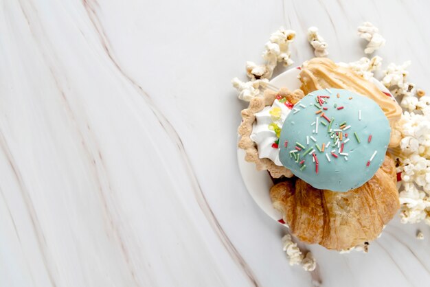 Variedad de alimentos dulces en un plato con palomitas de maíz sobre una superficie con textura