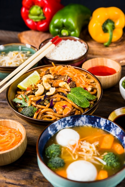 Variedad de deliciosa comida tailandesa con palillos en mesa de madera