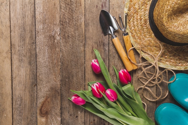 Variedad de herramientas de jardinería con flores sobre mesa de madera