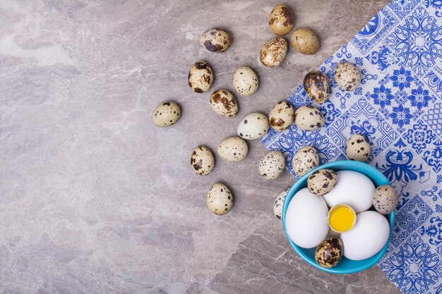 Variedad de huevos en taza azul y en el suelo.
