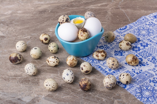 Variedad de huevos en una taza sobre superficie gris