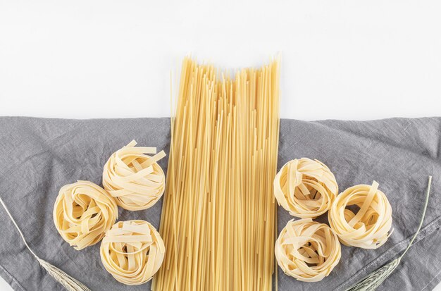 Variedad de pasta cruda sobre mantel gris. Foto de alta calidad