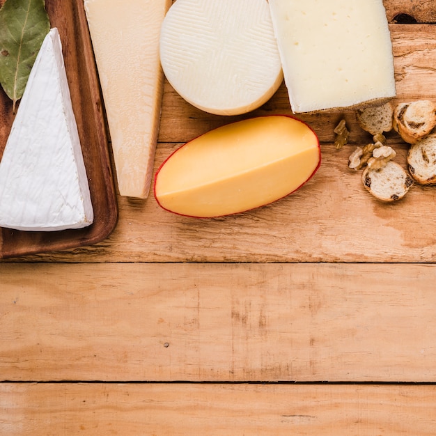 Foto gratuita variedad de quesos; pan y nueces en mesa con espacio para texto.