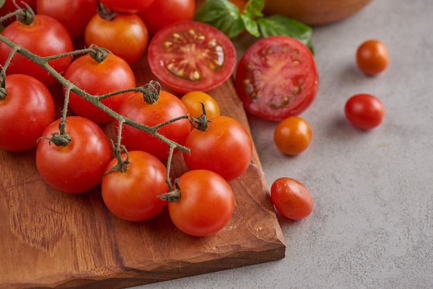 Variedad roja fresca de tomates con especias de albahaca, pimienta. Concepto vegetal de tomate. Comida de dieta vegana. Cosecha de tomates.