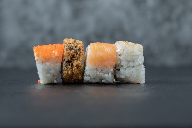 Variedad de rollos de sushi aislados en mesa gris.