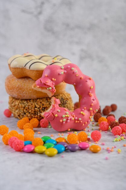 Una variedad de rosquillas y rosquillas que muerden fresas yacían delante.