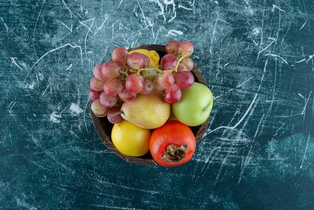 Variedad de sabrosas frutas en balde de madera.
