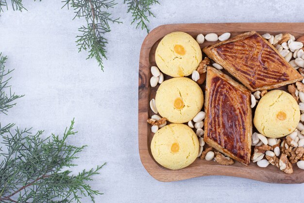 Variedad de sabrosas galletas en tablero de madera con nueces.