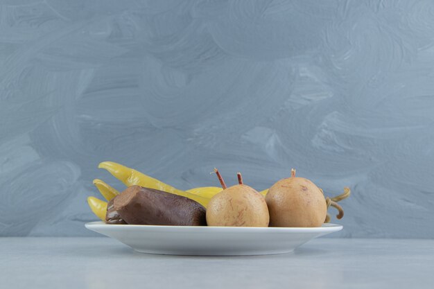 Variedad de verduras y frutas fermentadas en un plato blanco.