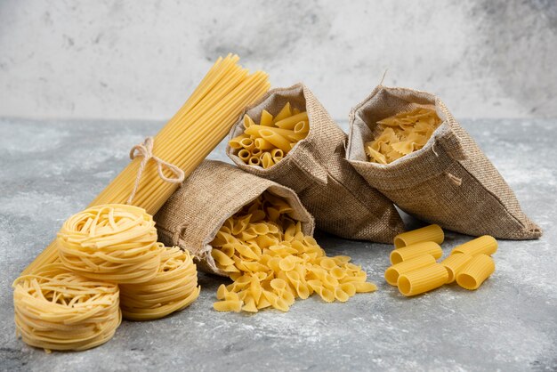 Variedades de fideos y pastas en cestas rústicas y mesa de mármol.